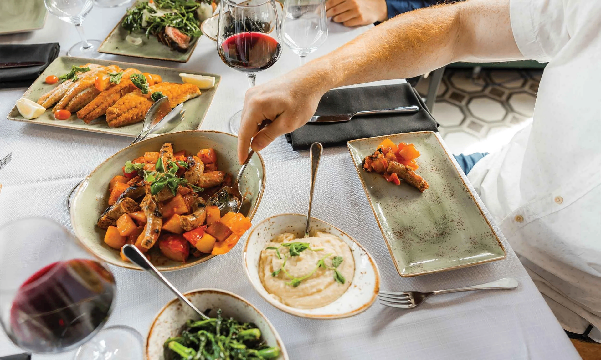 CORSO family-style dinner mid-flow with sausage, squash, polenta and wine served overhead